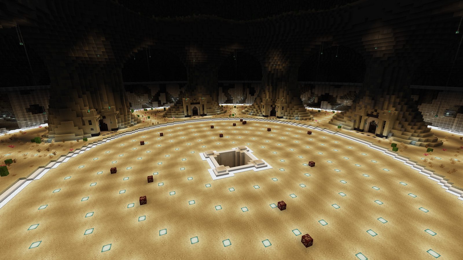 A wide sand arena floor lit by rings of lights around a central shaft