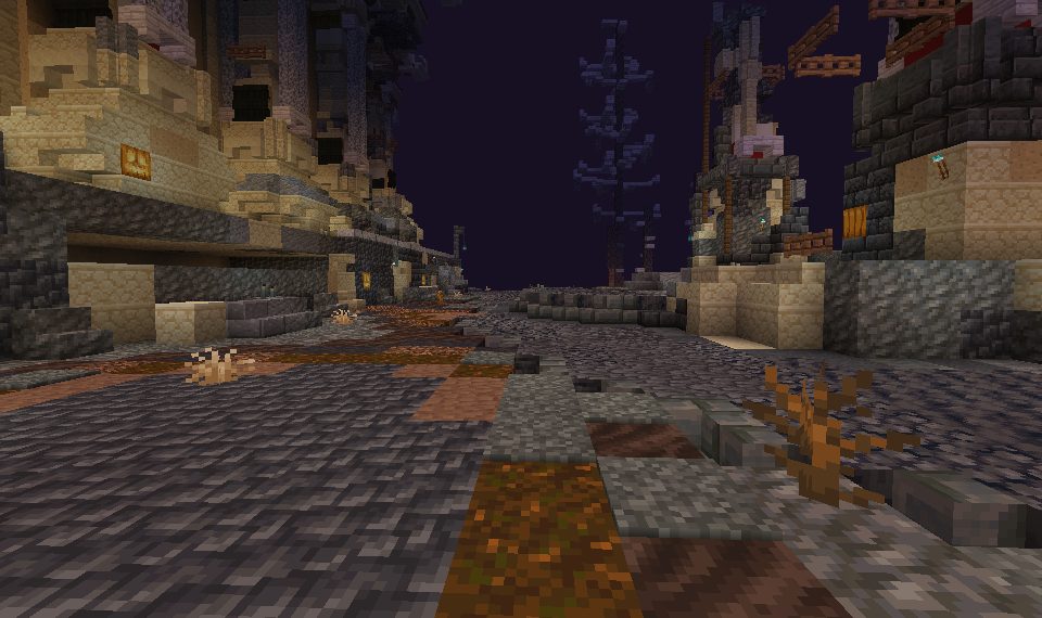 A dark cobbled road through ruined sandstone buildings at night